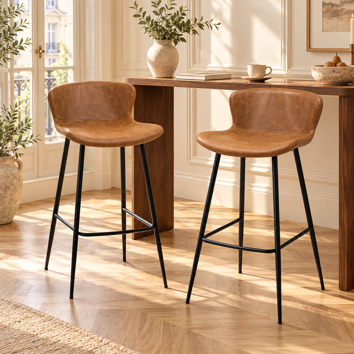 Deux tabourets hauts chocolat devant une console haute en bois dans un intérieur lumineux à moulures et parquet clair.