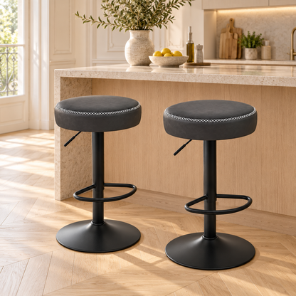 Deux tabourets anthracite à assise ronde devant un îlot en bois clair.