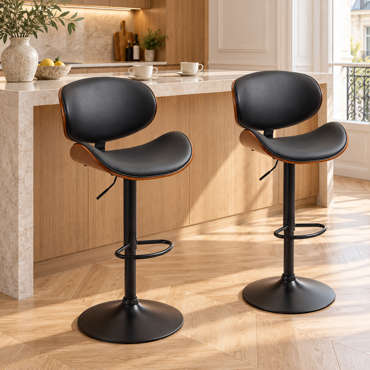 Deux tabourets de bar noirs à bordure bois devant un comptoir dans une cuisine moderne à moulures et parquet clair en chevrons.