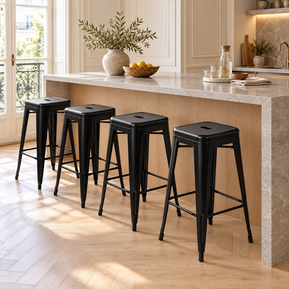 Quatre tabourets de bar métalliques noirs installés dans une cuisine chaleureuse à parquet clair et moulures.