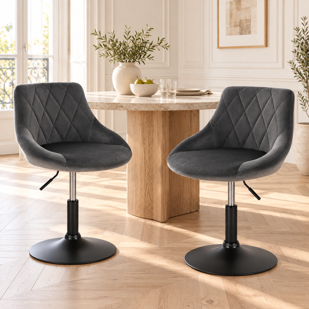 Deux chaises grises en velours à pied noir près d’une table dans un intérieur lumineux